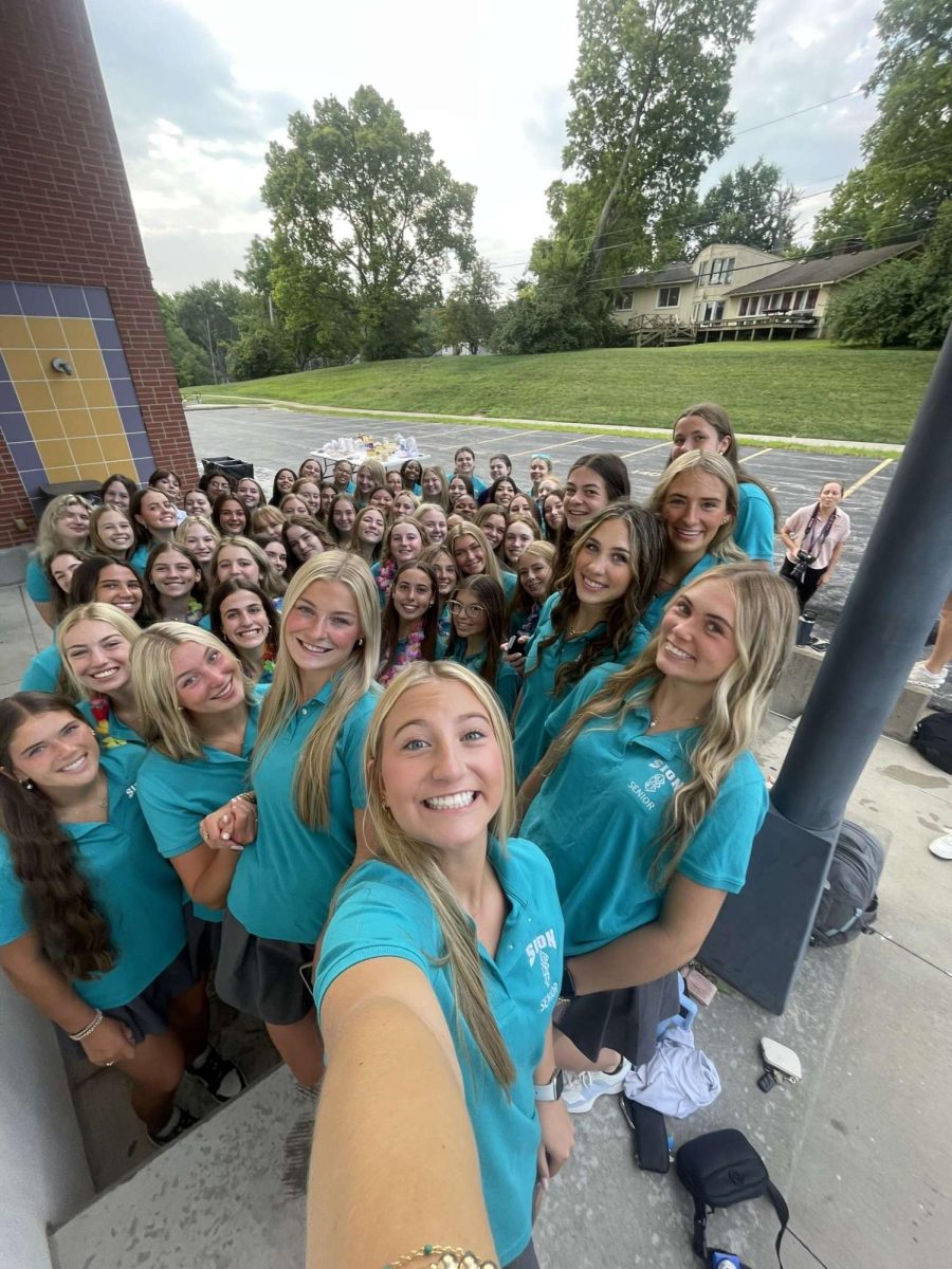 Senior Smiles
Huddling together, the class of 2025 celebrates the kick-off to their senior year on August 18. Senior Francie Kiethline was asked to take a group picture by her fellow classmates.  "I went to pose on the ledge and all of a sudden someone handed me their phone and I was in charge of taking the class picture," Keithline said. "I wanted to fit everyone so I took a point five and we all squeezed in tight which was so wholesome." 