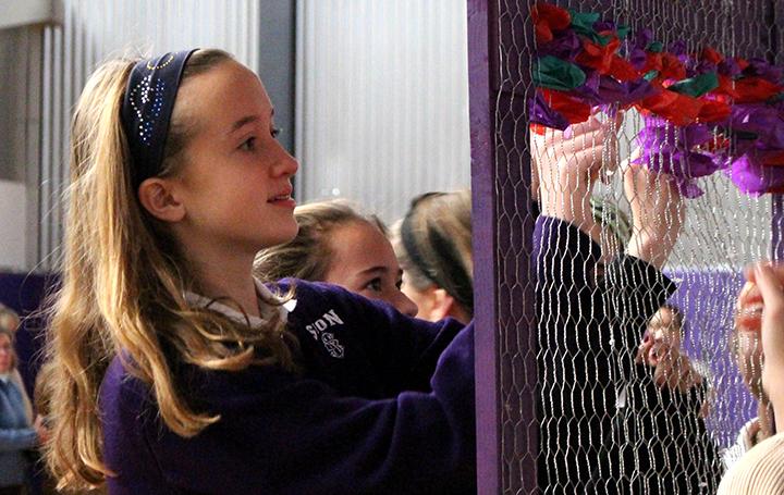 Freshman Meg Travis places a piece of red tissue paper through the wire wall at the Thanksgiving Prayer Service on Nov. 18. 