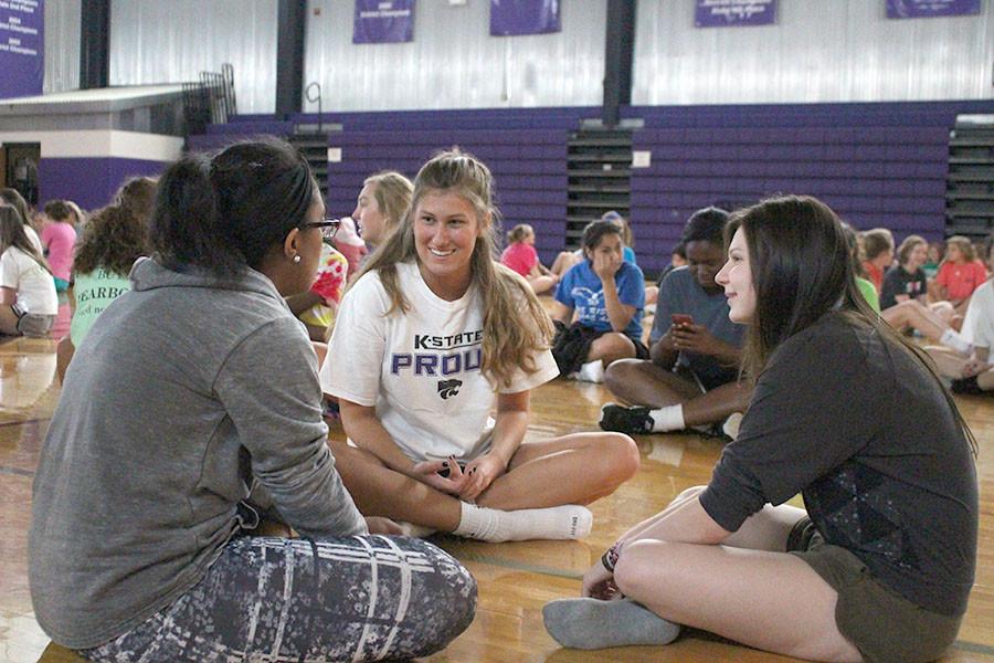 Seniors Mena Beralign and Ellen Lilek converse with freshman Gwyn Powell while waiting for partner yoga to start.