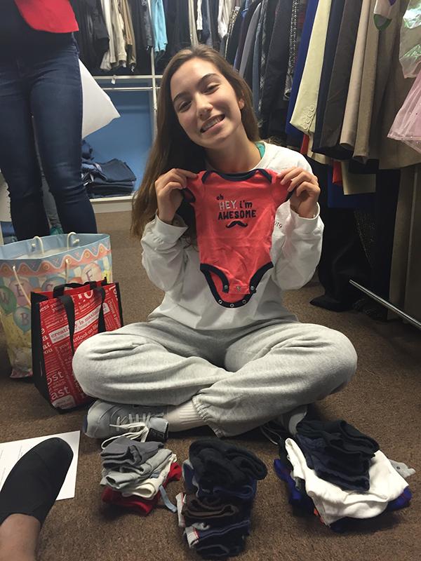 Freshman Isabella Thornton sorts baby clothes for Safe Home.