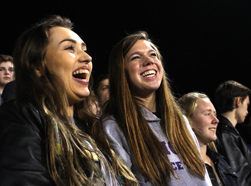 Seniors Olivia Neal and Hannah Valentine laugh as the sharks and minnows scamper around the football field.