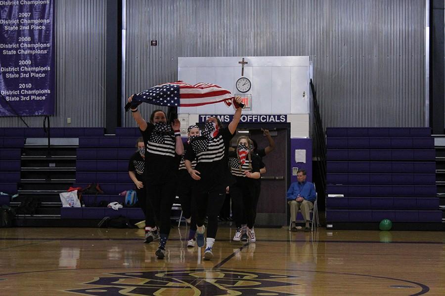 Senior student council runs into the gym carrying an American flag during the parade of nations.