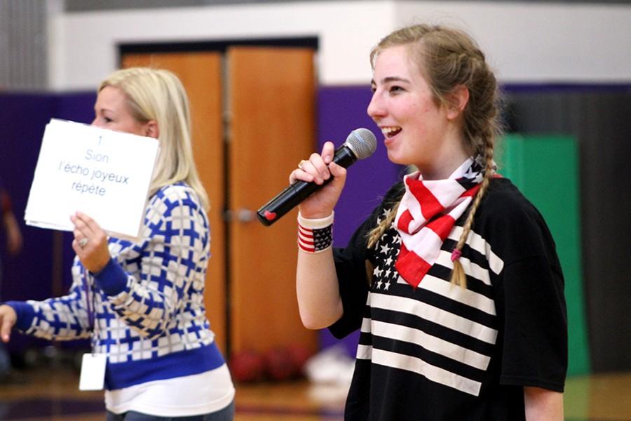 Senior Katie Pendergast leads students in the school song alongside French teacher Liz Bono.