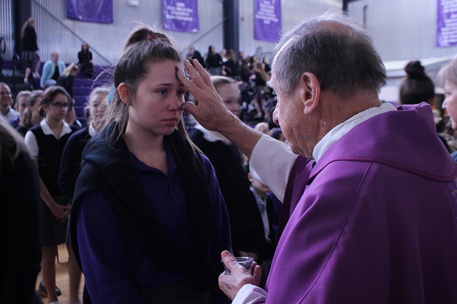 Junior Esobel Moore receives ashes from Father Jerry Waris at the Ash Wednesday Mass on Feb. 20.