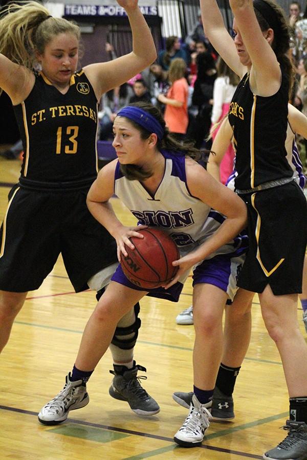 Sophomore Sarah Totta looks for a pass while trapped under the basket by St. Teresa's seniors Kathleen Herrington and Grace Kitts. Varsity Basketball lost 40-56 in the Jan. 29 game. 