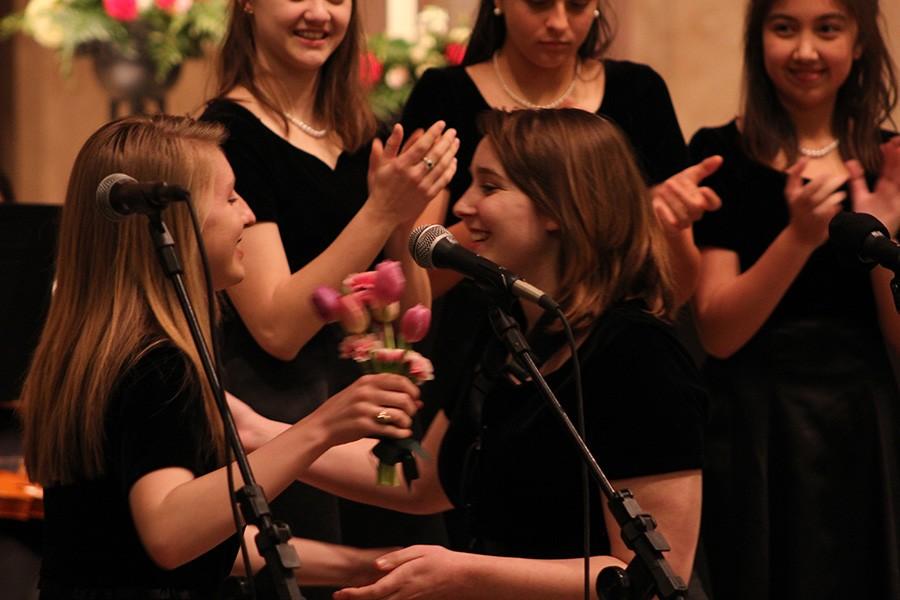 Senior violinist Isadora Comens gives junior Zoe Mulkey a hug after Mulkey presented her with flowers to recognize her dedication to the symphony for the past four years.