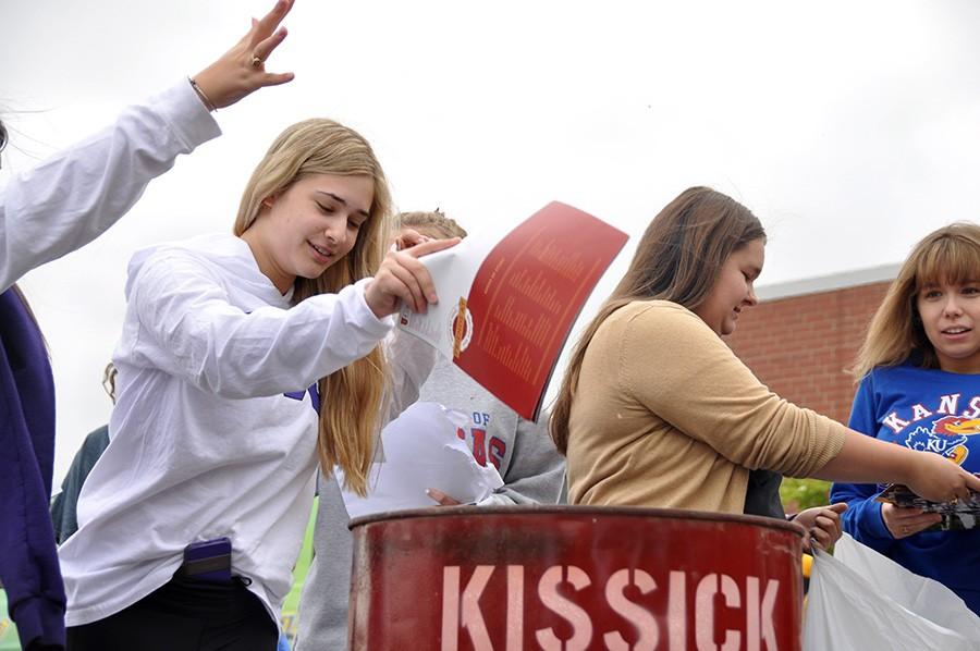 Seniors Alexis Cucchiara, Anna Sell and Madison Masillionis throw old college brochures in a bonfire. 