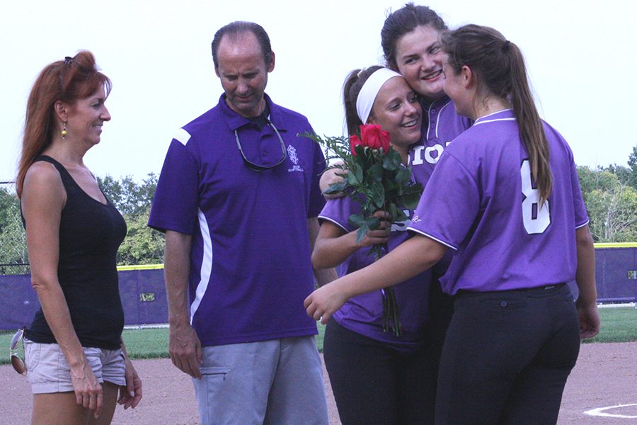 Juniors Kelly Nugent and Reagan Amato embrace senior Madeline Dercher as Dercher's parents stand near.