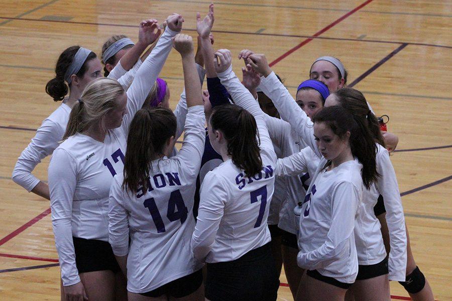 Varsity volleyball player gather in a huddle before the start of the second set.