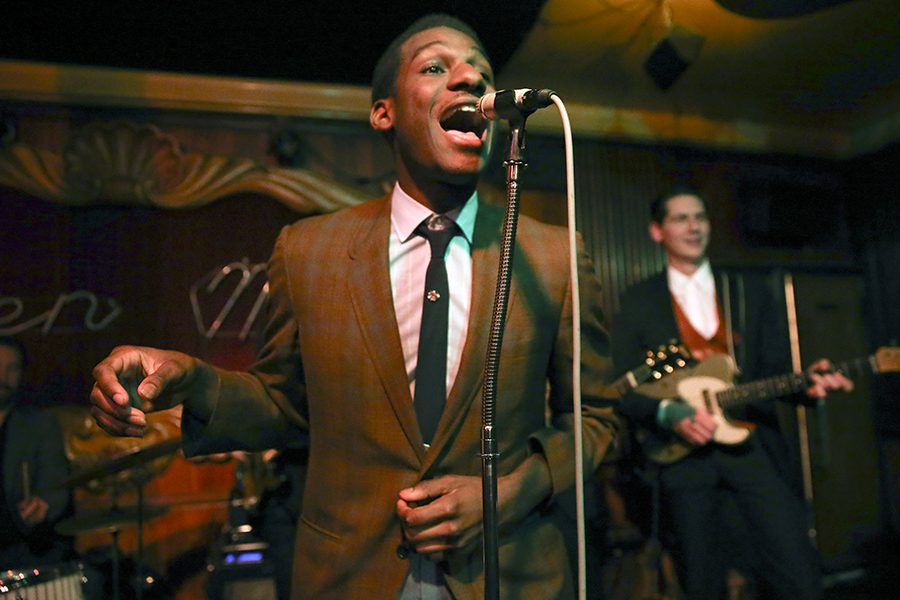 Leon Bridges wears his signature look, a semi-formal vintage suit, while performing with his band.