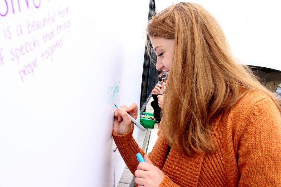 Senior Erin Quinn smiles while writing on the Sion Wall.