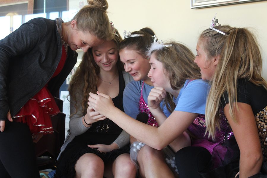 Sophomores Molly Conway, Savannah Childress, Maddie Griffin, Emily Koca and Mimi Wright gather around to look at their photos in their "Toddlers and Tiaras" themed costumes.