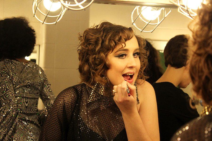 Senior Zoë Mulkey applies lipstick before the beginning of the first act. 