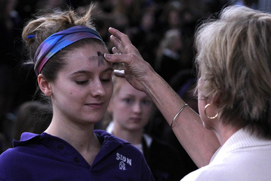 Senior Marie Orrick receives ashes from Assistant Division Head for Student Life Fran Koehler.