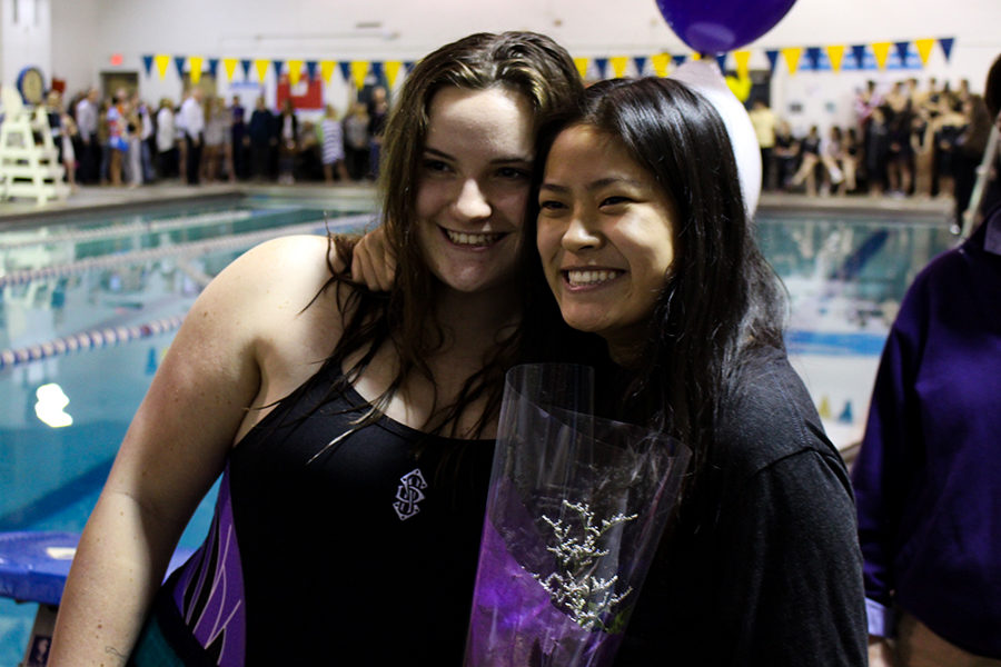 After recieving flowers from junior Emma Cruciani on swim senior night Jan. 24, senior Ann Huff puts her arm around Cruciani and smiles alongside her to pose for a picture.