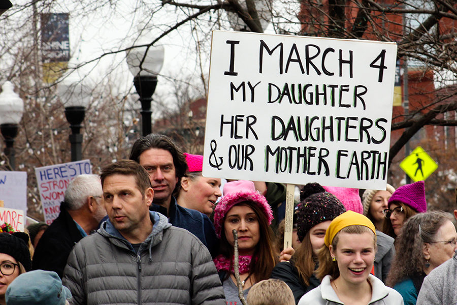 A woman holds a sign above a crowd of people while marching down Massachusetts Street during the Woman’s March in Lawrence, Kansas Jan. 20.