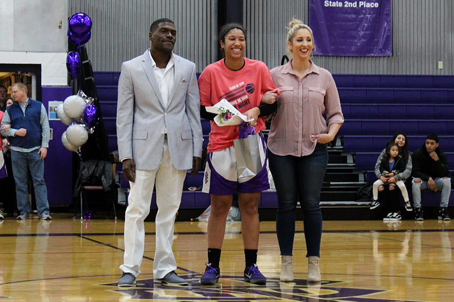 Senior Amaya Adams laughs with her parents Dexter and Denise Adams while the senior’s accomplishments, including being a member of the baking club, are read over the speaker.