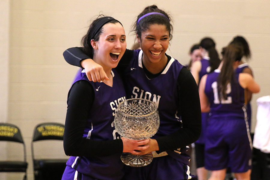 After beating St. Teresa’s Academy 50-42, seniors Meghan Frerking and Amaya Adams hold the Irish Cup while laughing and posing for a picture Saturday, Feb. 24.