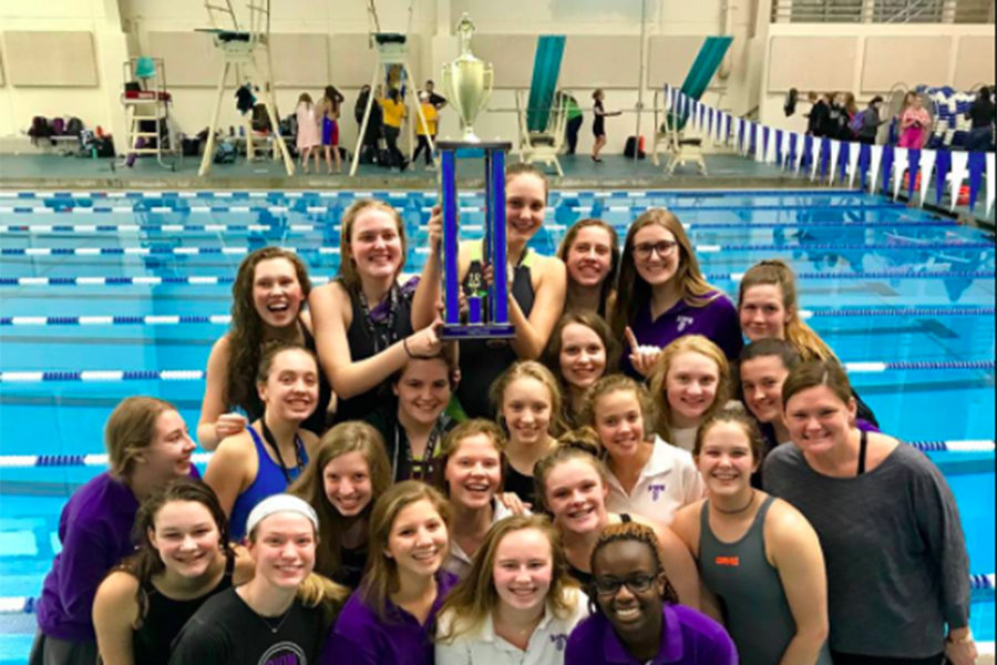 The swim team poses for a picture with seniors Lexi Smith and Ellie Magsaman holding up the first place trophy after singing the school song to celebrate their win at the Independent League Championship.