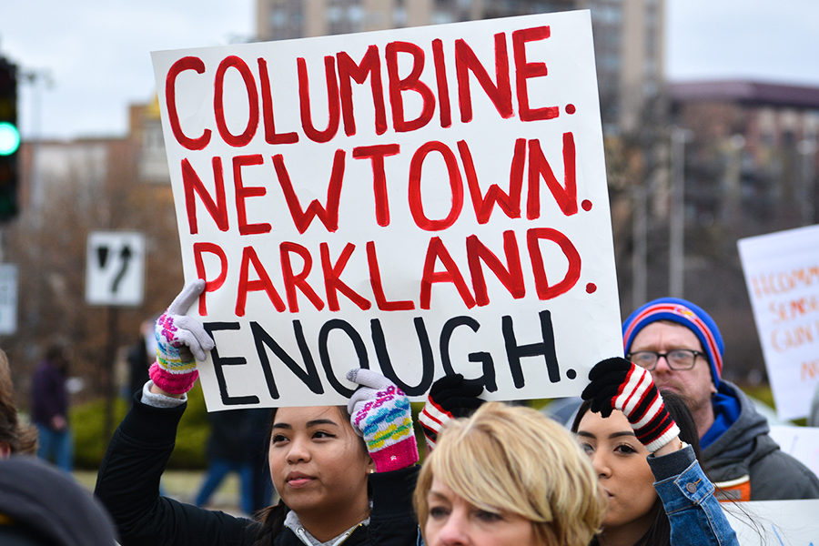 Two girls march down Emanuel Cleaver II Blvd holding a sign above their heads to advocate for gun control at the March For Our Lives in Kansas City, Missouri March 24.