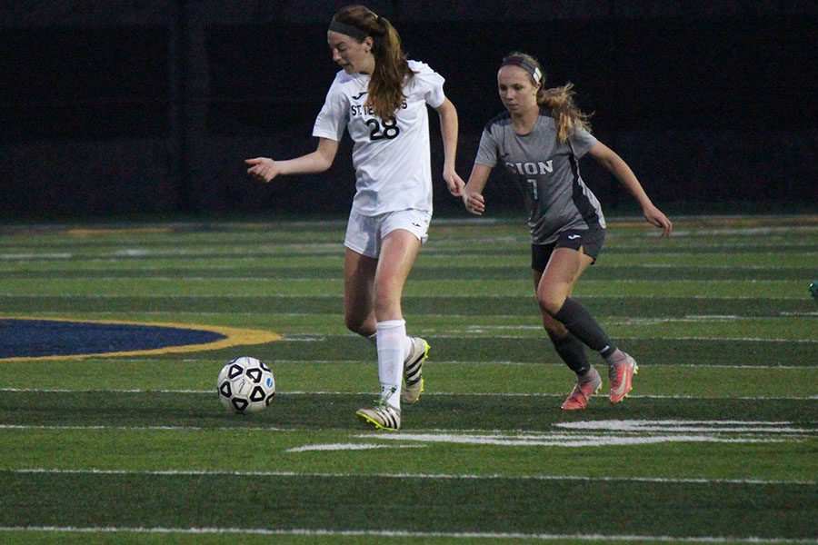 During the annual Mo-Kan varsity soccer tournament’s championship game versus St. Teresa’s Academy on March 28, freshman Katelyn Brinkman attacks STA sophomore Brooke Fallis for possession of the ball.