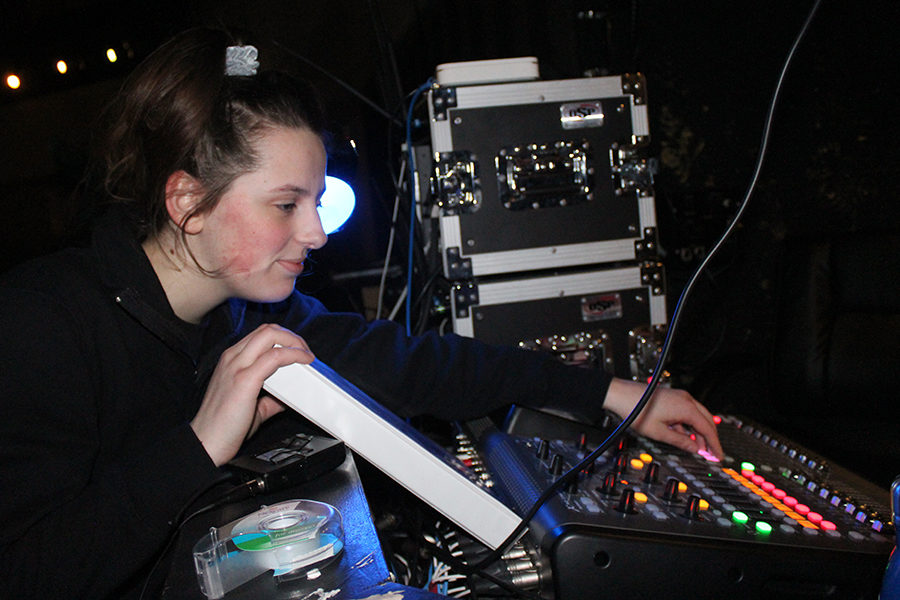 Before dress rehearsal for the musical “Into the Woods” Jan. 24, junior Nora Weir checks and fixes the mics for the performers.