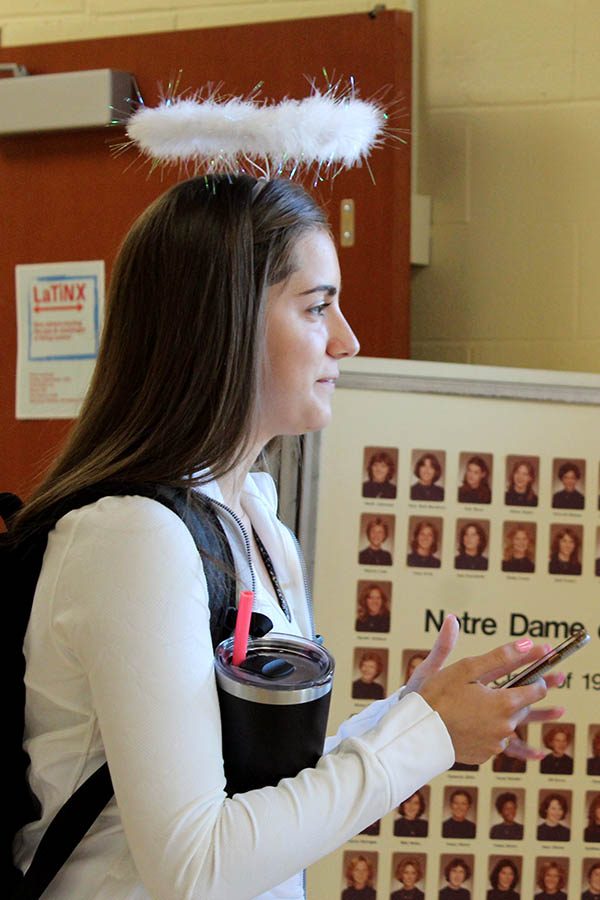 Senior Caroline Boessen texts on her phone before school Sept. 11. For the third day of Spirit Week, students participated in the Devils and Angels theme. 