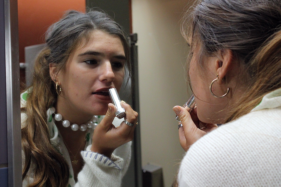 In between classes, Senior Reilly Jackoboice applies lipstick in the South C bathroom Sept. 11. For day four of spirit week, seniors dressed as senior citizens.  