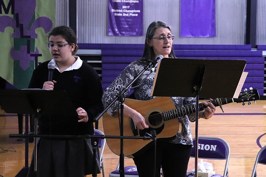 Senior Maya Bair and religion teacher Stephanie Pino-Dressman leads the school in song during the annual reconciliation service March 12.