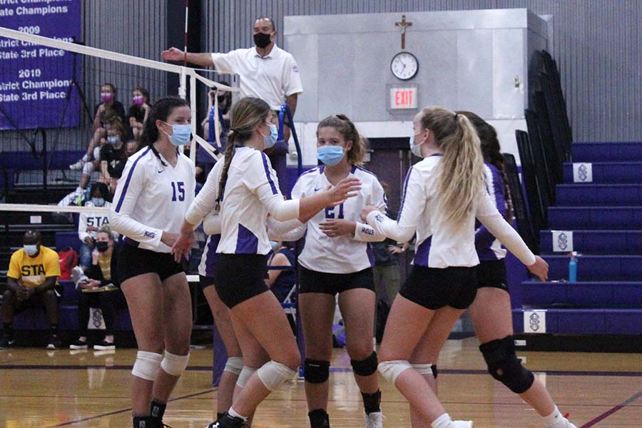 Seniors Shannon Karlin and Brynna Dow, sophomore Brynna Fitzgerald and junior Bridgette Conner huddle after a point during the volleyball game against St. Teresa's Academy in the gym on Sept. 8.