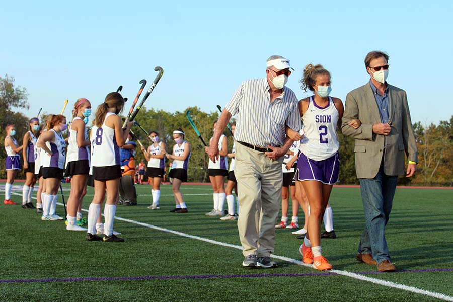 Senior Ruby Wright walks with her father and her grandfather while being presented during the field hockey Senior Night on Sept. 10. on the field. 