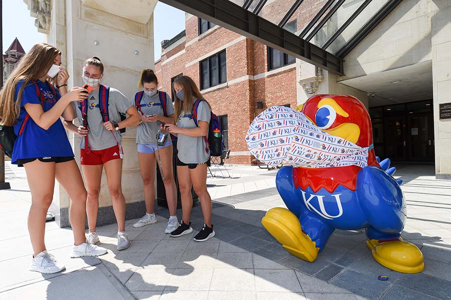 On the first day of classes, Karli Schmidt, from left, Jenny Mosser, Anezka Szabo and Molly Schultz, all members of the Kansas volleyball team, wait for a bus Monday, Aug. 24, 2020, on campus at the University of Kansas in Lawrence. Students returned for classes with COVID-19 safety protocols in place. (Tammy Ljungblad/The Kansas City Star/TNS)