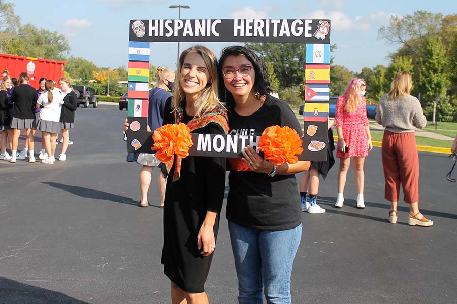 Social Sciences teacher Morey Williams and Spanish teacher Señora Gonzalez pose holding the Hispanic Heritage Month sign in the circle drive.