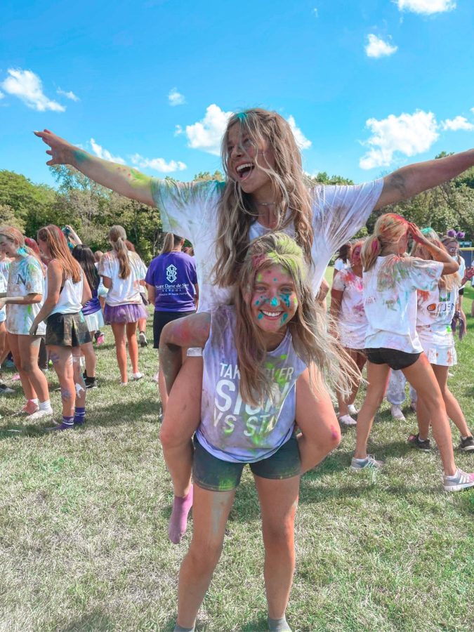 Senior Kate McCarthy rides on senior Taylor Crouch's back for a photo taken at the color throw this year.