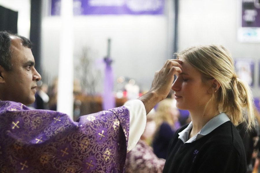 Senior Grace Townsend is anointed with ashes by Father Thomas 