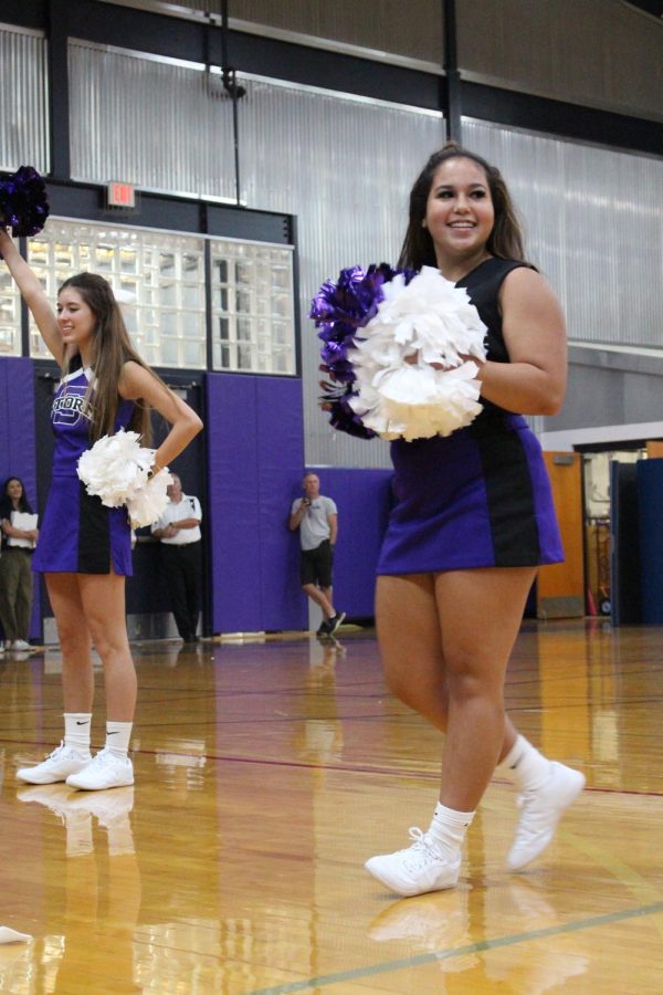 Junior Gianna Collins ruffles her pom poms during the cheer team's performance 