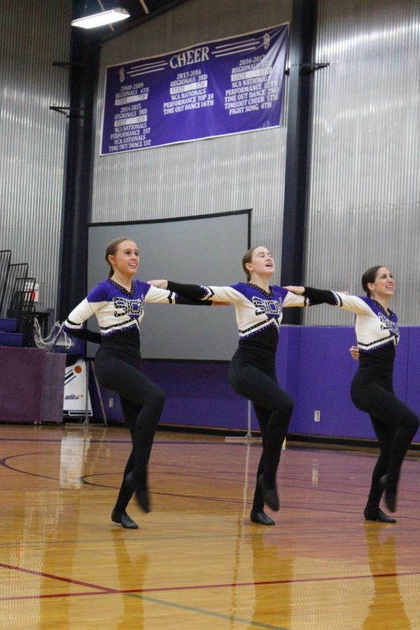 Reese Chambers '22, Zoey Chambers '25, and Stella McClure '25 kick as high as they can during the dance team's performance 