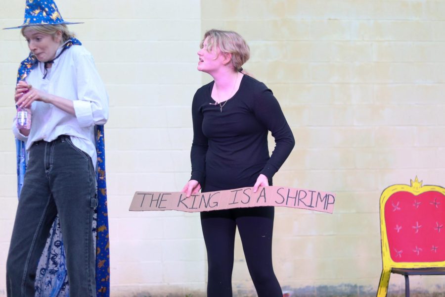 Senior Mo Browne trying not to laugh as sophomore Kate Schneeberger holds up a sign reading "The king is a shrimp."