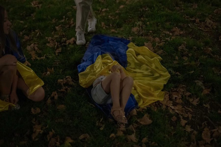 Veronica Timakina, 6, is covered by a Ukrainian flag as she lies in the grass.