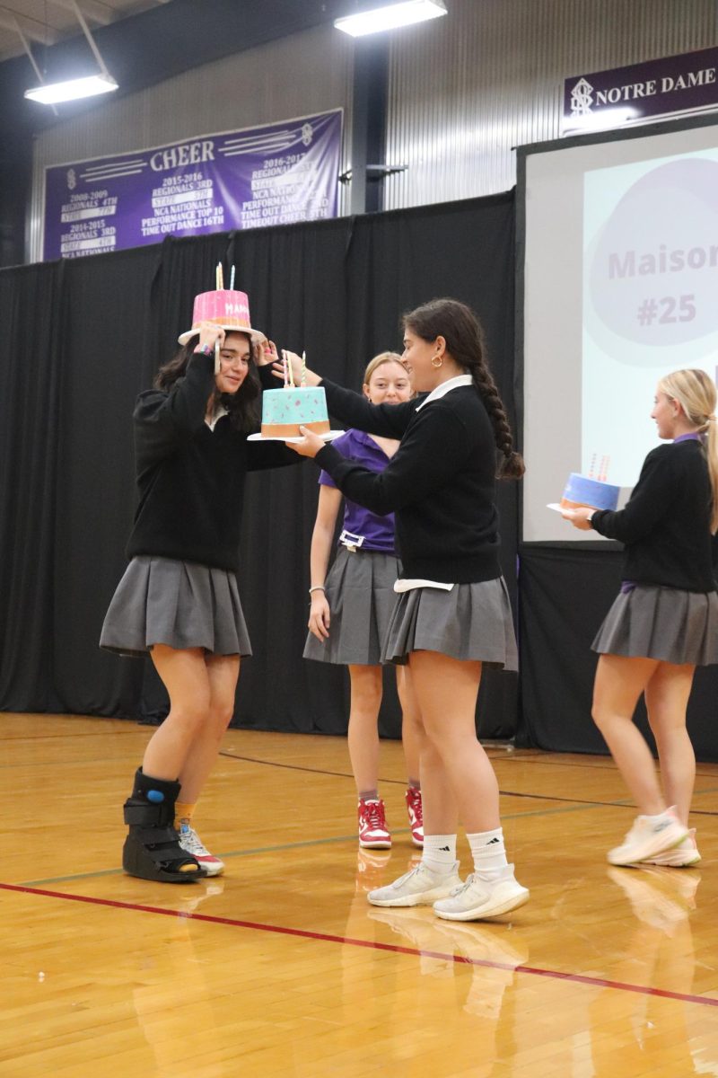 Squatting slightly, freshman Maddie Bridges accepts her birthday cake-themed beanie from senior Camryn Markey on August 19. For Bridges, the Beanie ceremony was followed by a welcoming celebration featuring brownies made with applesauce. “My favorite thing was probably the beanie ceremony because it was like a nice welcome to everyone,” Bridges said, “and it kind of got everyone into their own family group, especially if they were struggling to find friends.”